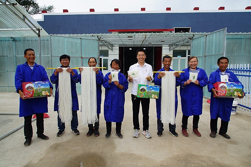 Sun JinLong displaying his glass noodles alongside factory employees